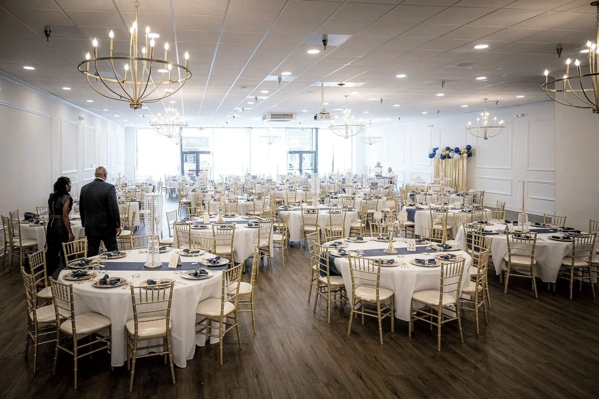 Een feestzaal met gedekte ronde tafels wordt klaargezet voor een evenement