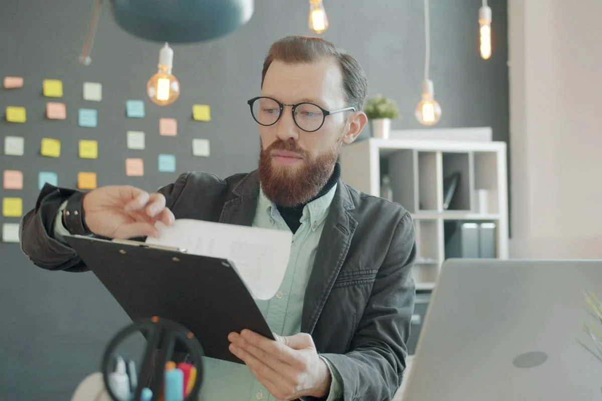 Een officemanager bekijkt documenten op een klembord in een opgeruimd kantoor
