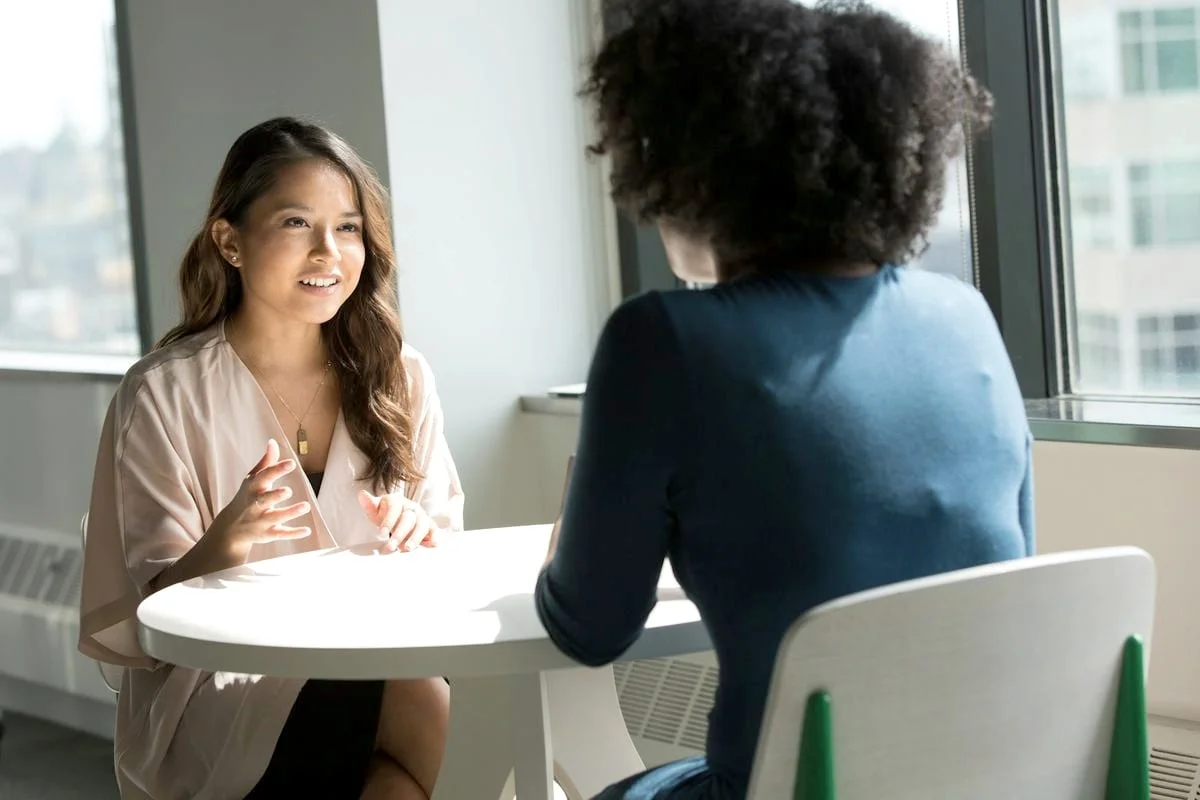 Twee vrouwen voeren een ontspannen kennismakingsgesprek aan een ronde tafel