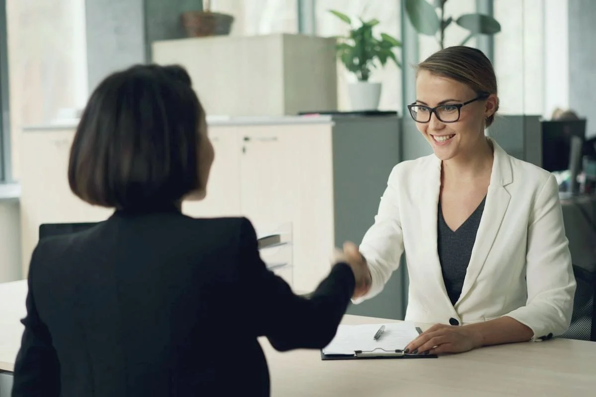 Een HR-medewerker schudt een kandidaat de hand aan het begin van een sollicitatiegesprek