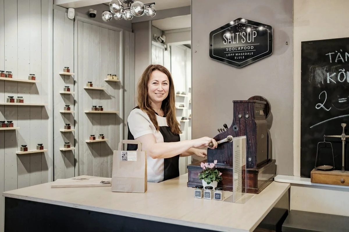 Een winkeleigenaar helpt achter de toonbank van een kleine, lichte winkel