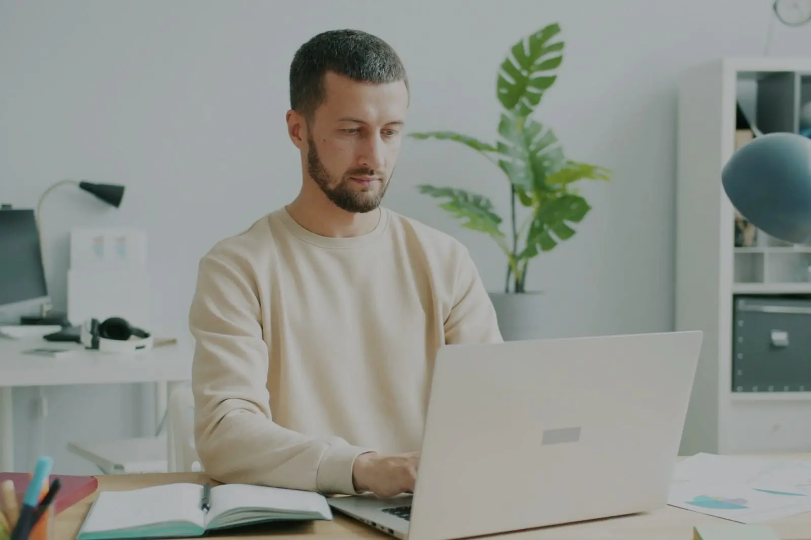 Een professional werkt geconcentreerd op een laptop aan een opgeruimd bureau met planten